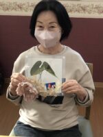入居者が手工芸活動で葉を使った制作物を持つ様子
